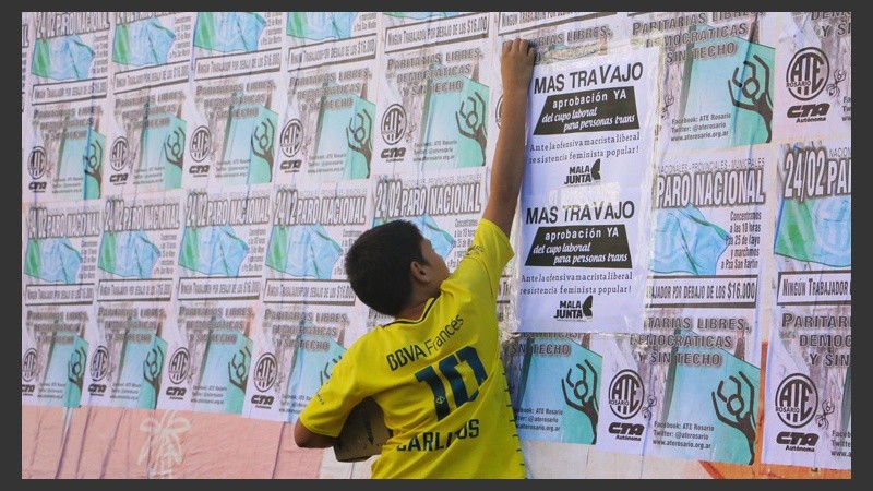 Un joven sobre unos afiches pegados anunciando la medida de protesta. (Alan Monzón/Rosario3.com)