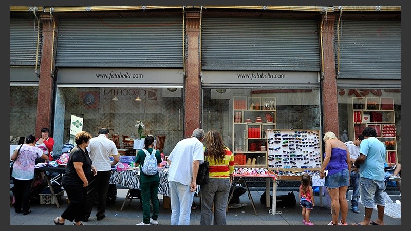 Peatones observan la mercadería pegada a una tradicional tienda de la ciudad.