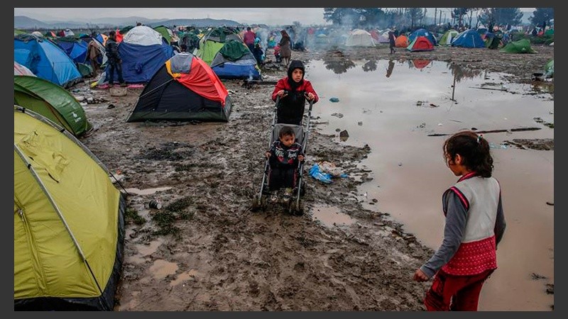 Refugiados caminan por el barro en un campamento cerca de Idomeni mientras esperan para cruzar la frontera con Macedonia.