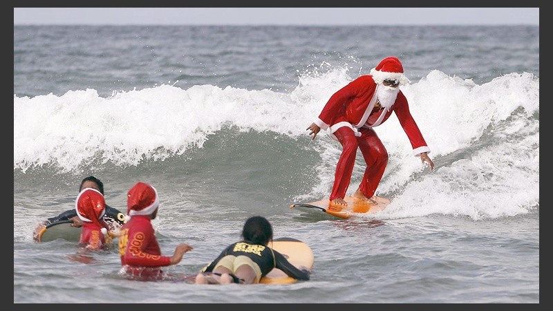 Papá Noel surfeando en una playa del Caribe.