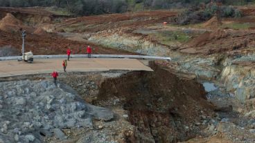 Trabajadores inspeccionan daños bajo el aliviadero auxiliar de la presa.