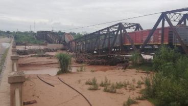 El tren sobre el puente caído y el río desbordado.