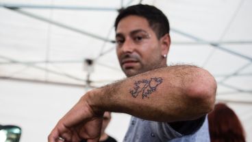 Un hombre muestra un tatuaje recién hecho de Malvinas. Se hacen gratis en una de las carpas.