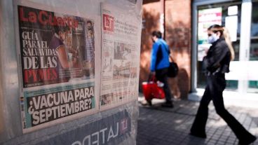 Una mujer camina junto a un quiosco de diarios monotemáticos en Santiago.