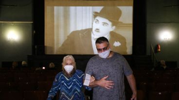 Una mujer mayor sale de vacunarse del brazo de un familiar, con Chaplin de fondo en la pantalla.