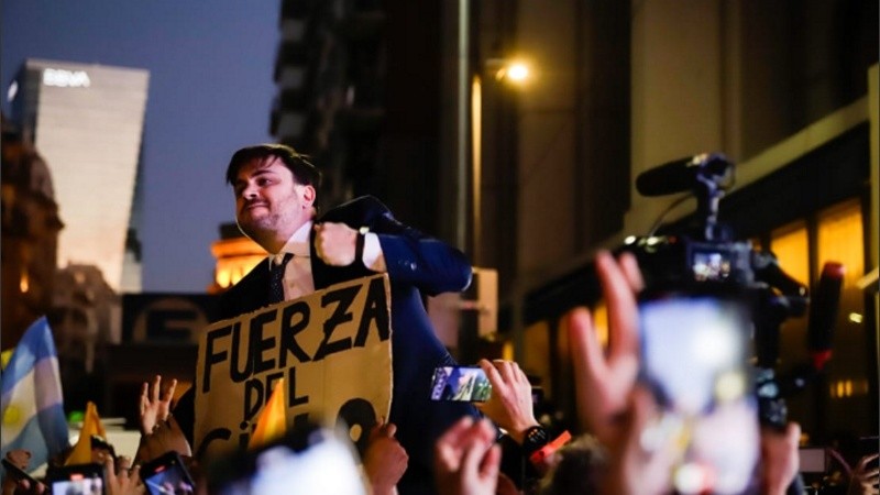 Ramiro Marra festejando en la calle trepado a las vallas.