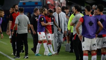 Banega deja la cancha de Estudiantes tras ver la roja, consolado por su compañero May.