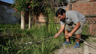 Talero reconecta una manguera de agua potable en medio de una zanja anegada.