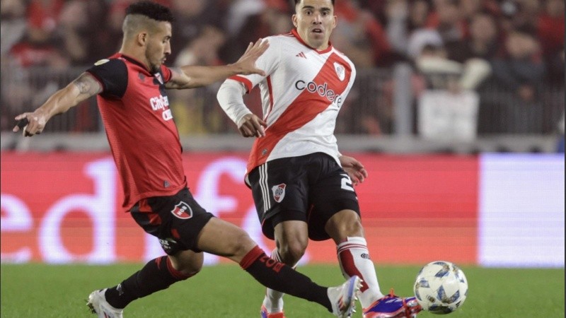 Cardozo y Acuña, que debutó en River, disputan una pelota en el Monumental.