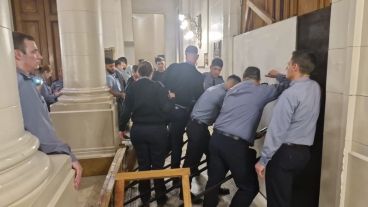 Los policías sostienen  la puerta de la Legislatura ante el embate de los violentos.